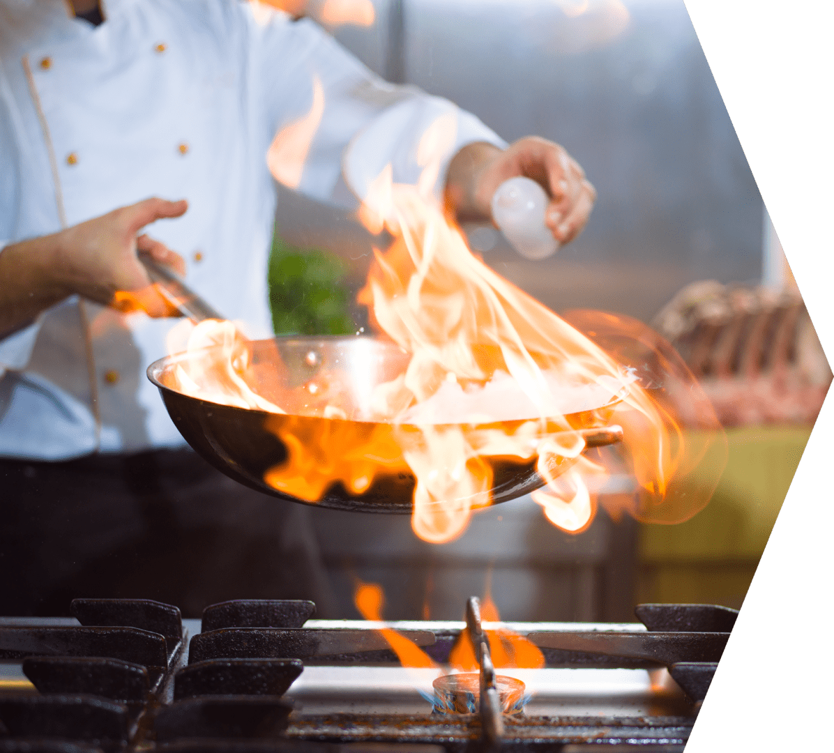 Chef cooking and doing flambe on food in restaurant kitchen